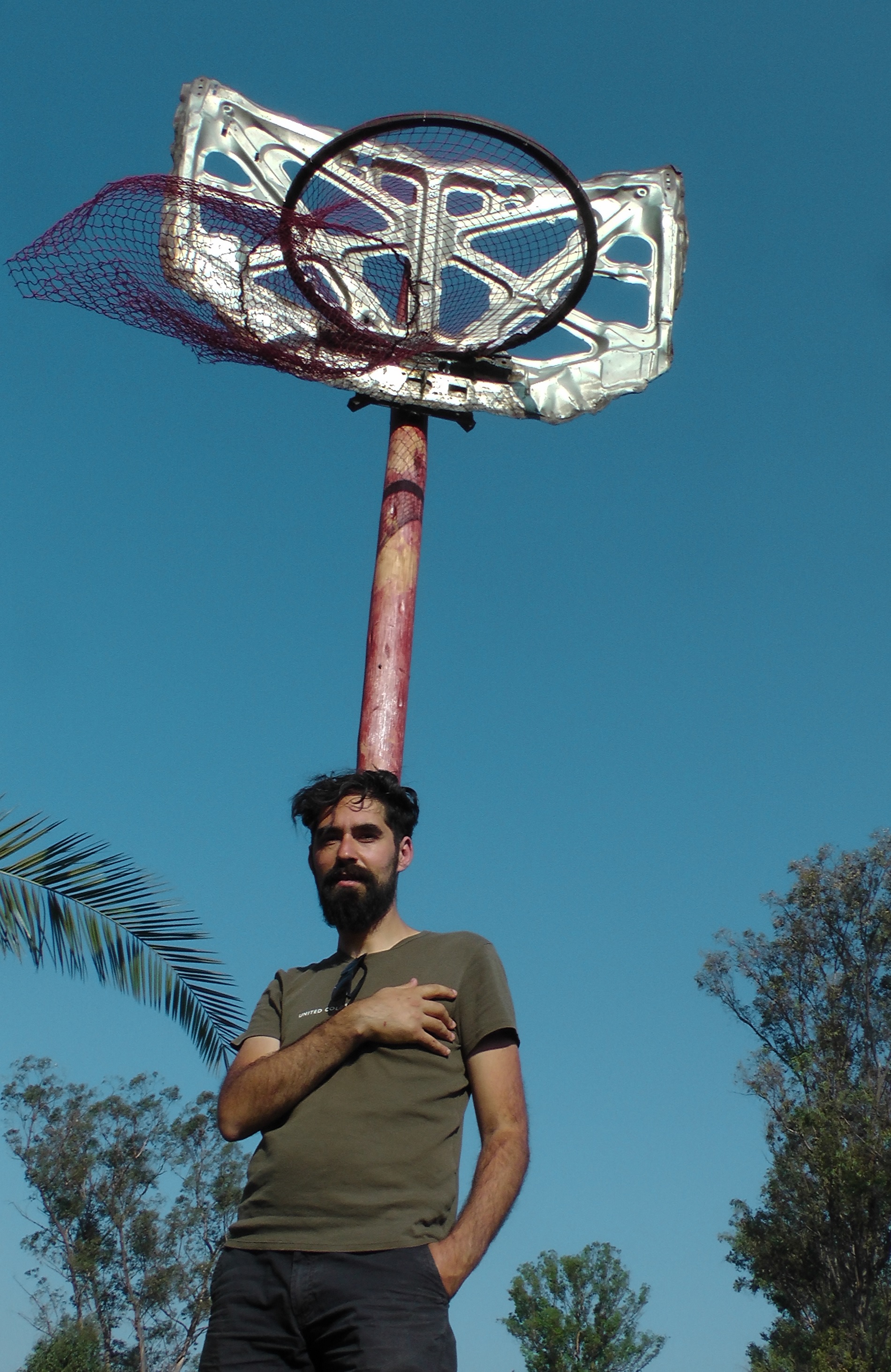 A man standing in front of a basketball hoop with blue sky behind him